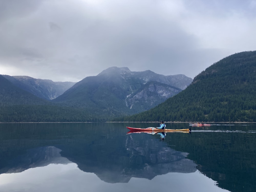 a person in a canoe on a lake with mountains in the background