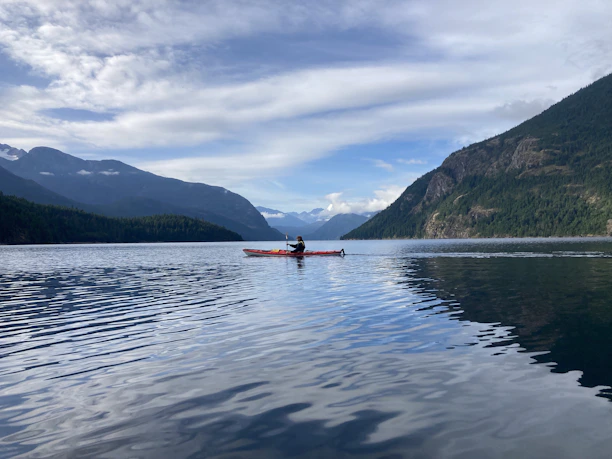 a person in a canoe on a lake with mountains in the background