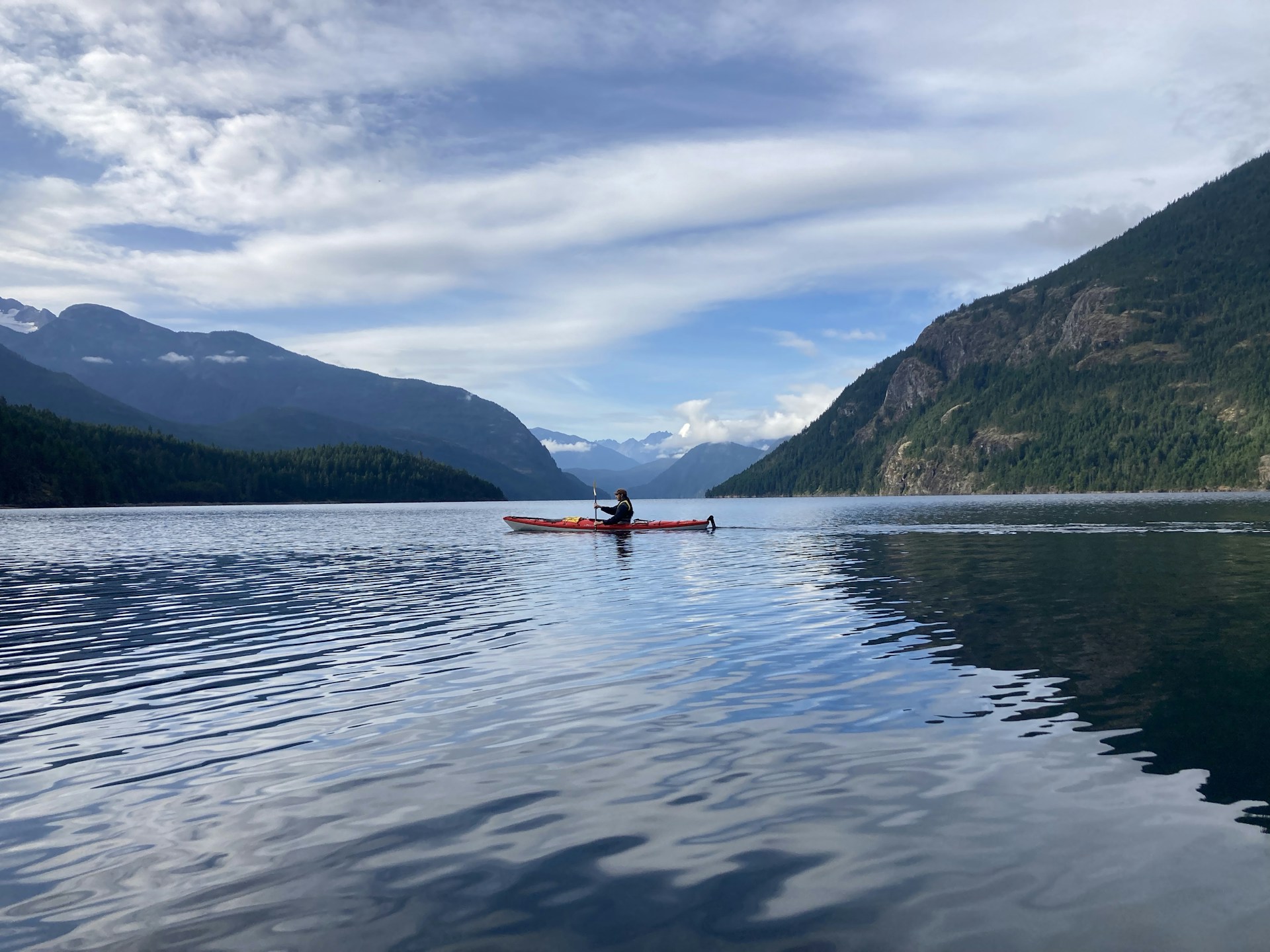 a person in a canoe on a lake with mountains in the background