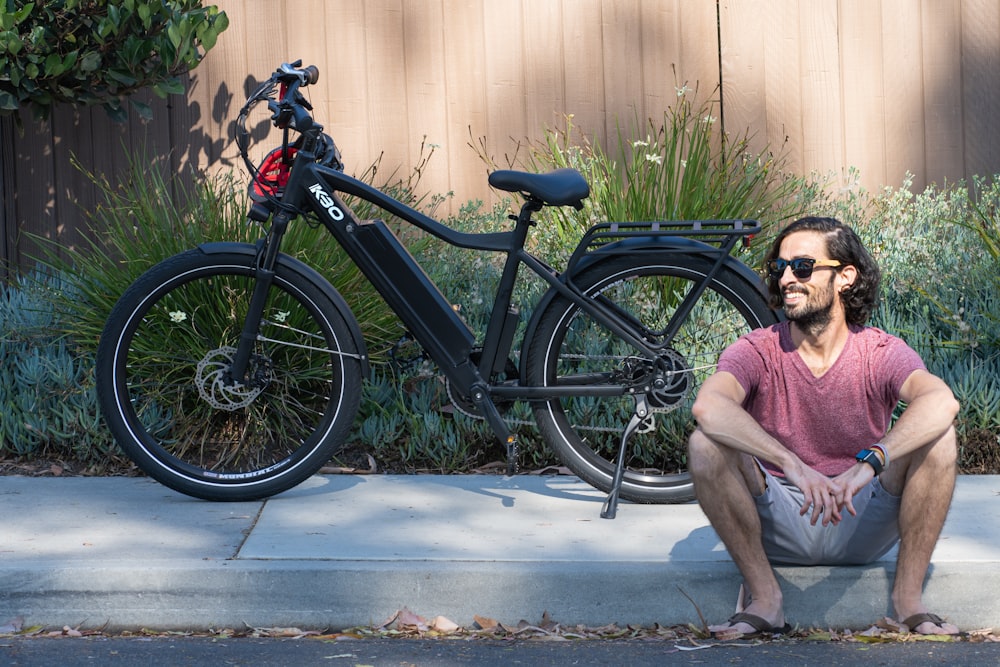 a man sitting on a curb next to a bike