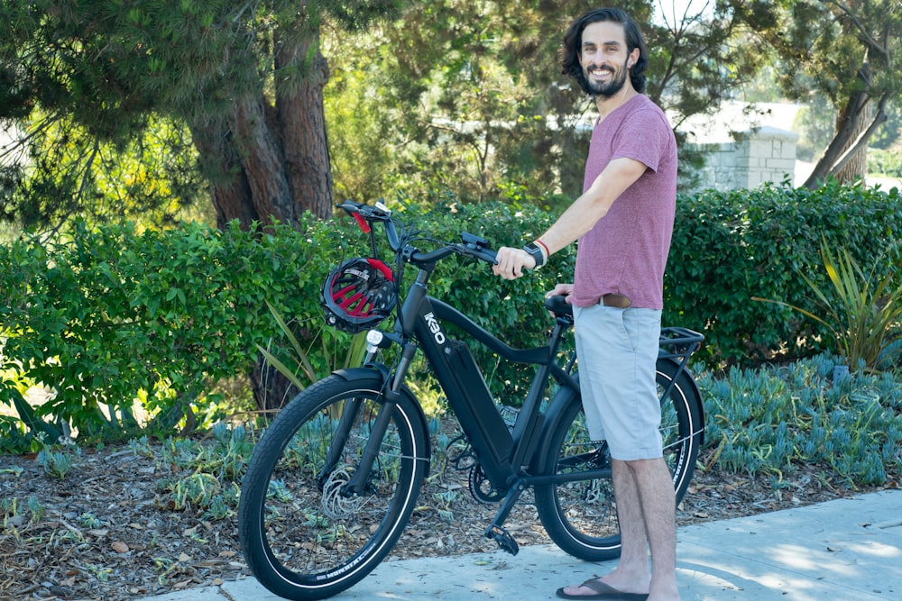 Ein Mann steht neben einem Fahrrad auf einem Bürgersteig