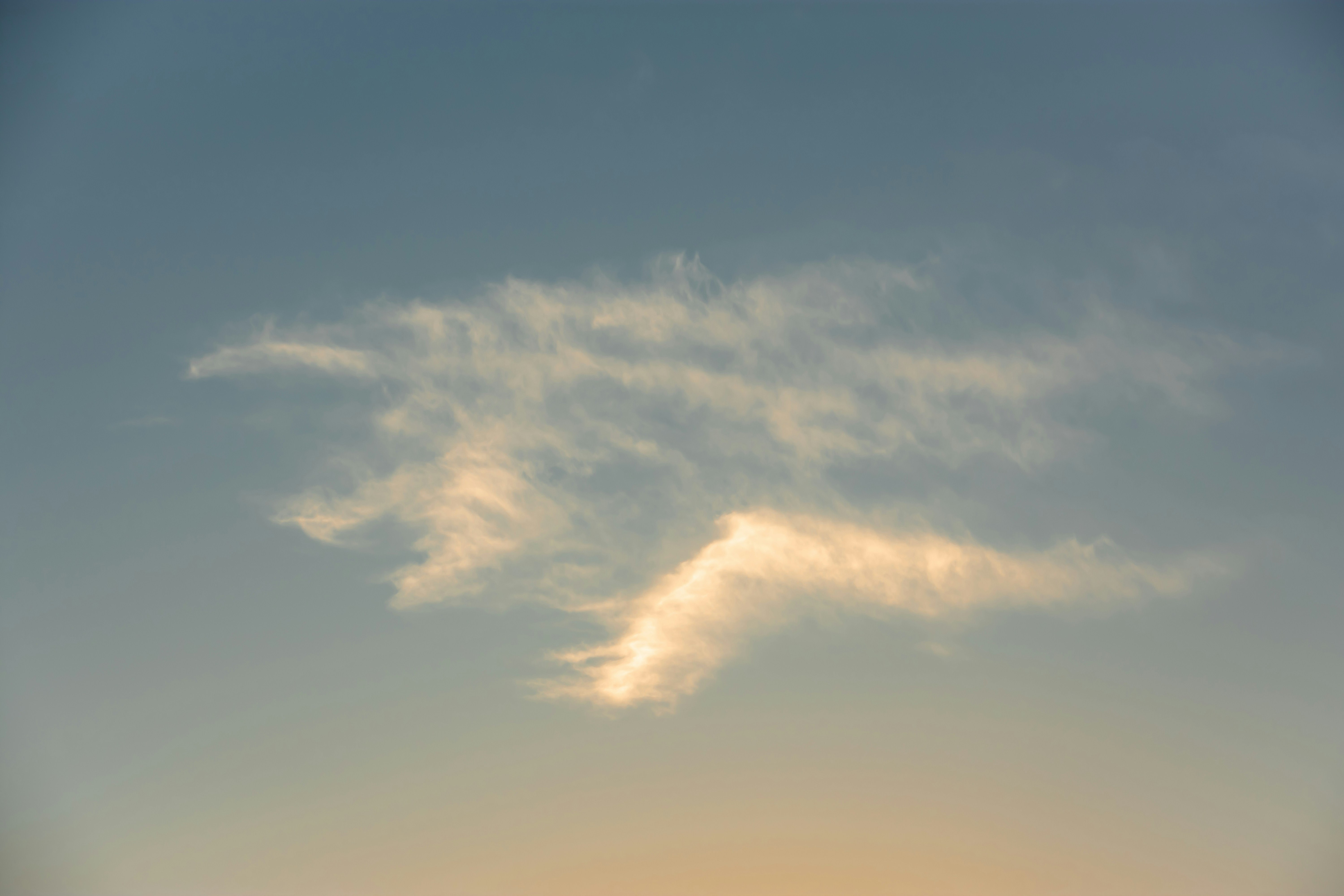 a plane flying in the sky at sunset