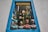 A decorative shop window framed by a blue border showcases four colorful ceramic busts of women wearing dotted clothing and headscarves. The window is filled with vibrant hanging decorations, including painted birds and hot air balloons, creating a lively and artistic atmosphere.