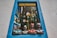 A decorative shop window framed by a blue border showcases four colorful ceramic busts of women wearing dotted clothing and headscarves. The window is filled with vibrant hanging decorations, including painted birds and hot air balloons, creating a lively and artistic atmosphere.