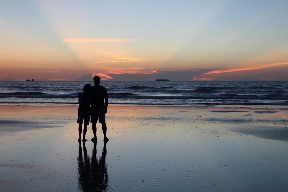 a couple of people standing on top of a beach