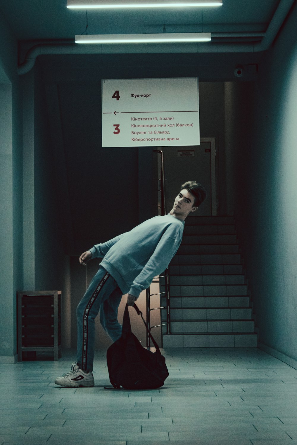 a man leaning on a suitcase in a hallway