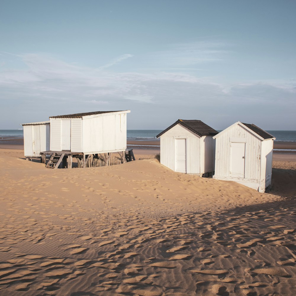 모래 해변 위에 앉아있는 두 개의 해변 오두막