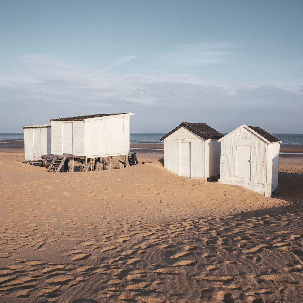 a couple of beach huts sitting on top of a sandy beach