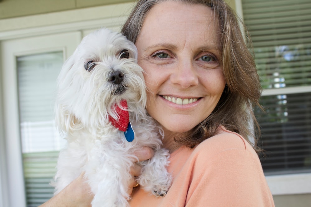 a woman holding a white dog in her arms