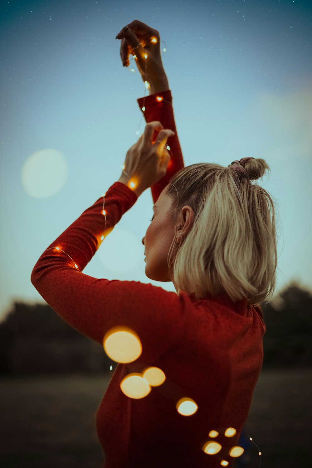 a woman in a red shirt holding a string of lights