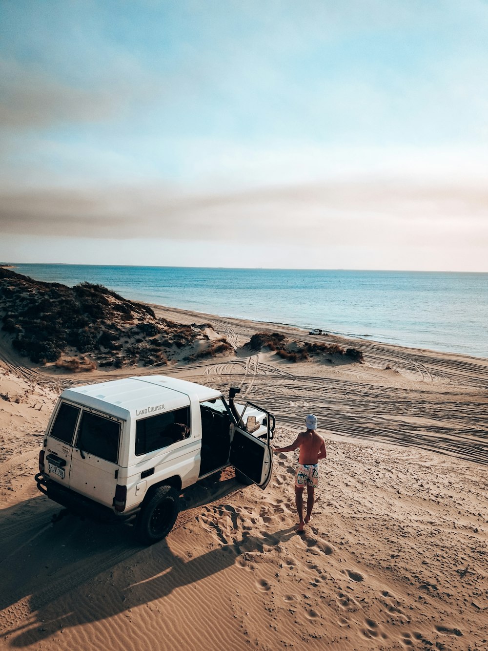Una furgoneta blanca estacionada en la cima de una playa de arena