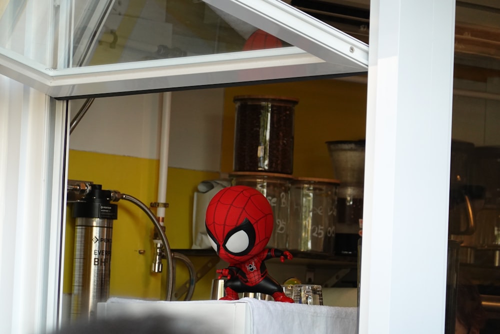 a spider - man doll sitting in a kitchen window