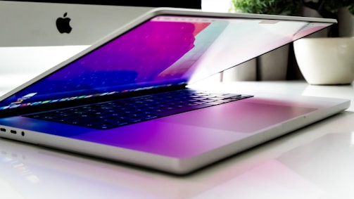 Modern laptop open on a desk with a high-resolution monitor in the background.