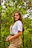 a young woman standing in the woods holding a cell phone