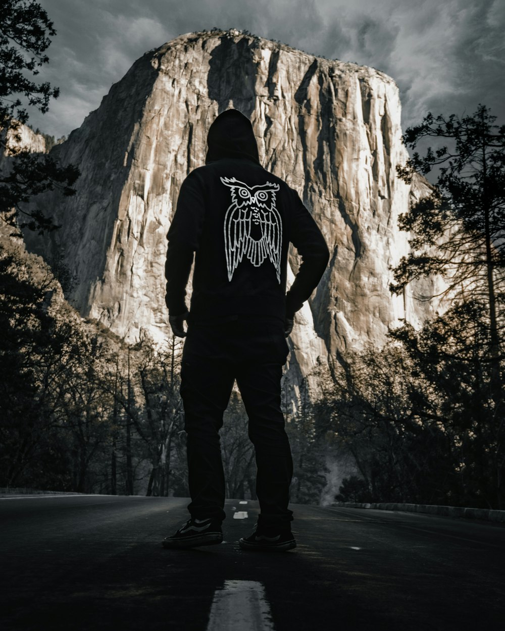 a man standing in the middle of a road in front of a mountain