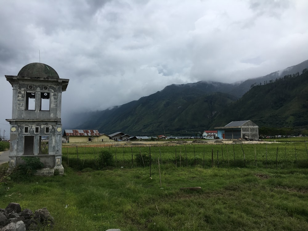 an old building in a field with mountains in the background