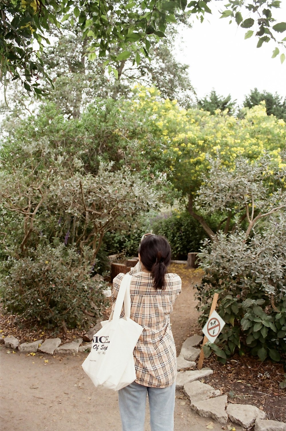 a woman walking down a path carrying a white bag