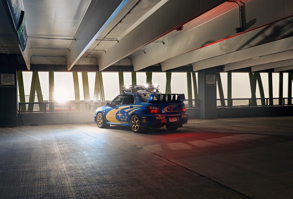 a blue and yellow car parked in a parking garage