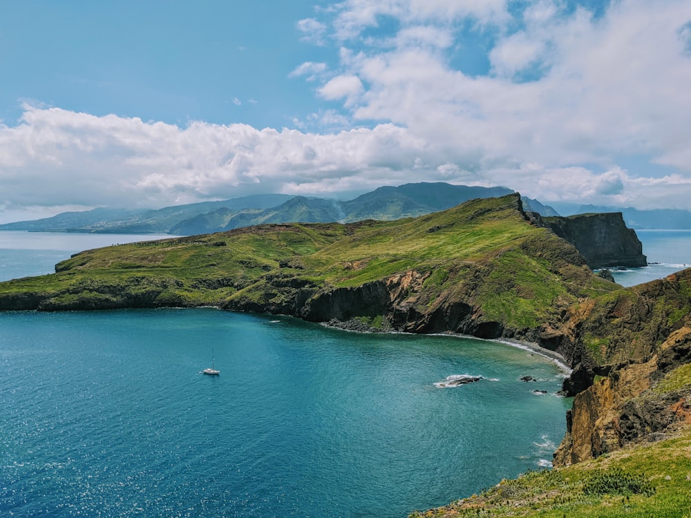 a body of water surrounded by a lush green hillside