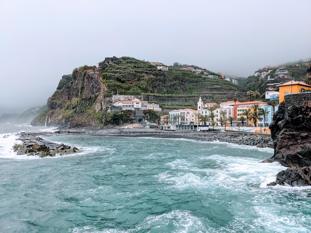 a body of water with houses on a hill in the background