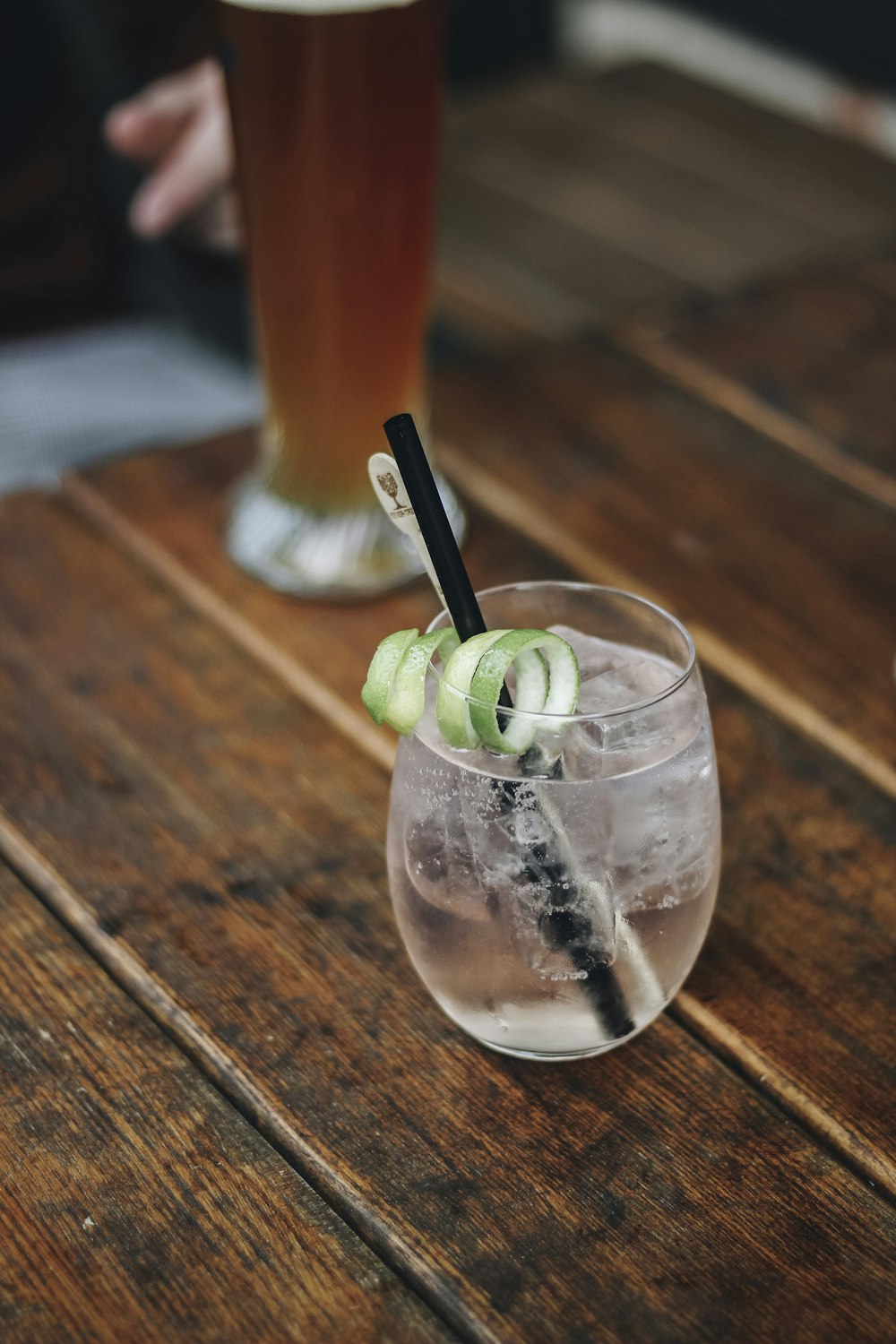 a wooden table topped with a glass filled with liquid and cucumbers