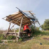 a man sitting on a bench under a wooden structure