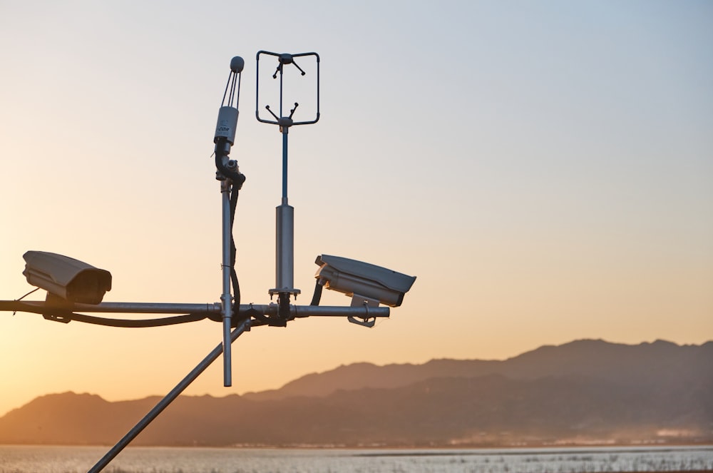 a couple of cameras sitting on top of a metal pole