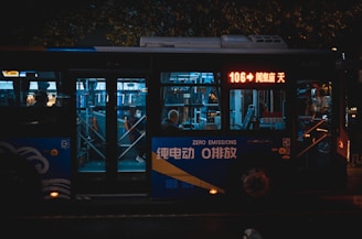 A city bus at night with illuminated signage and interiors. It is marked as a zero emissions vehicle. Passengers inside are visible through the windows, and the bus displays the route number 106 on a digital screen.