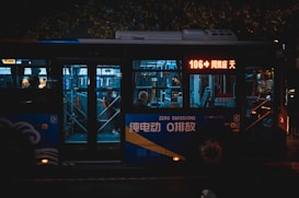 A city bus at night with illuminated signage and interiors. It is marked as a zero emissions vehicle. Passengers inside are visible through the windows, and the bus displays the route number 106 on a digital screen.