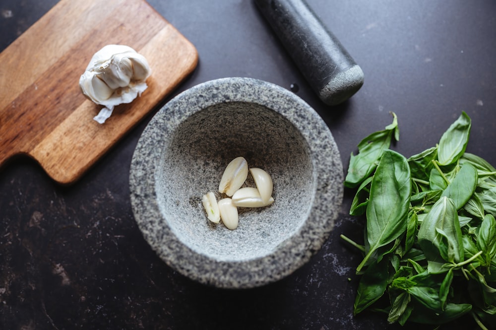 a bowl of garlic and spinach next to a knife