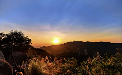 Sunset view over a mountain peak with a small tour group admiring the scenery.