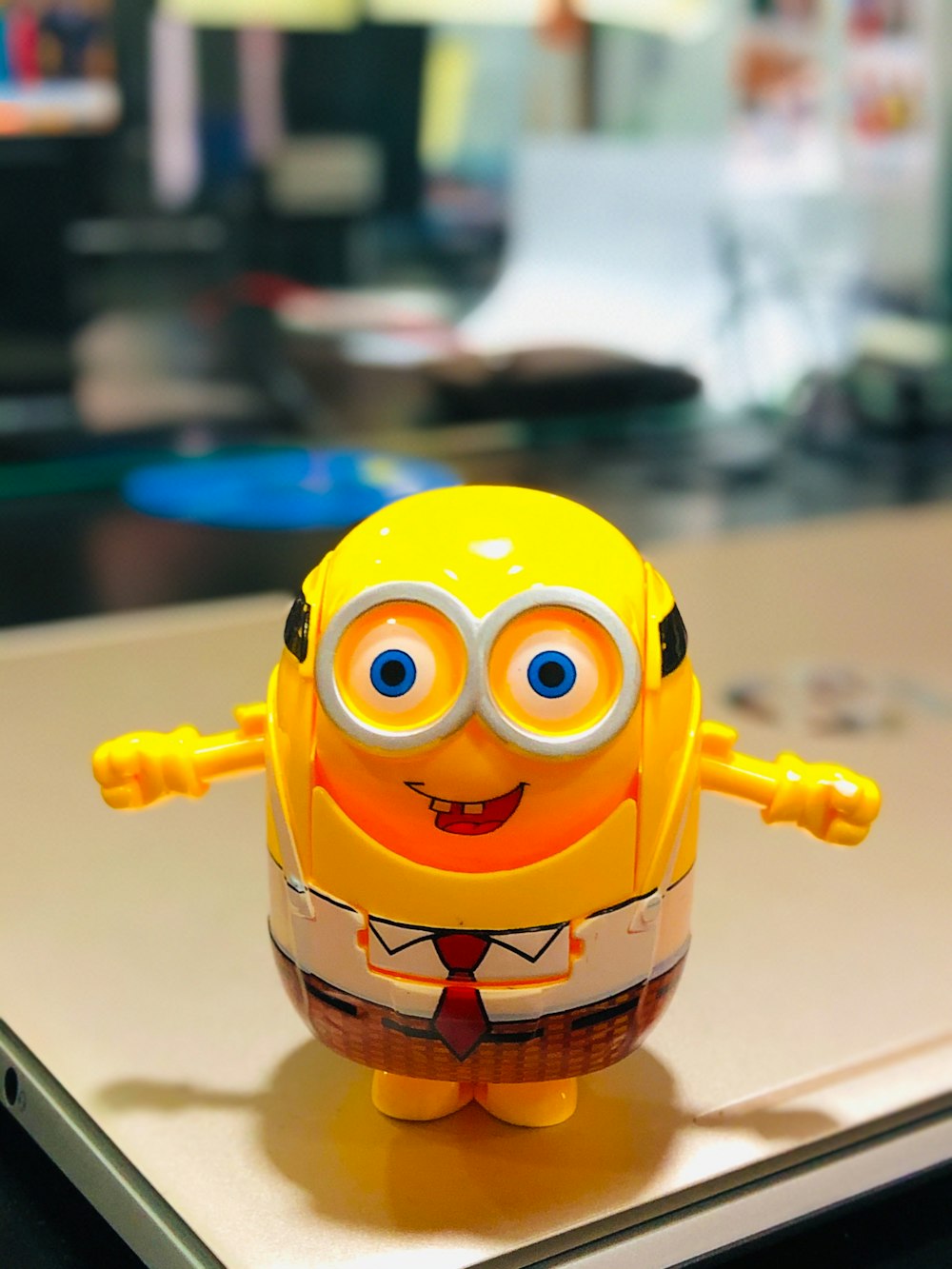 Un juguete amarillo con ojos y corbata sobre una mesa