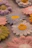 Close-up photo of a soft pastel-hued crocheted flower resting gently on a lavender cloth.