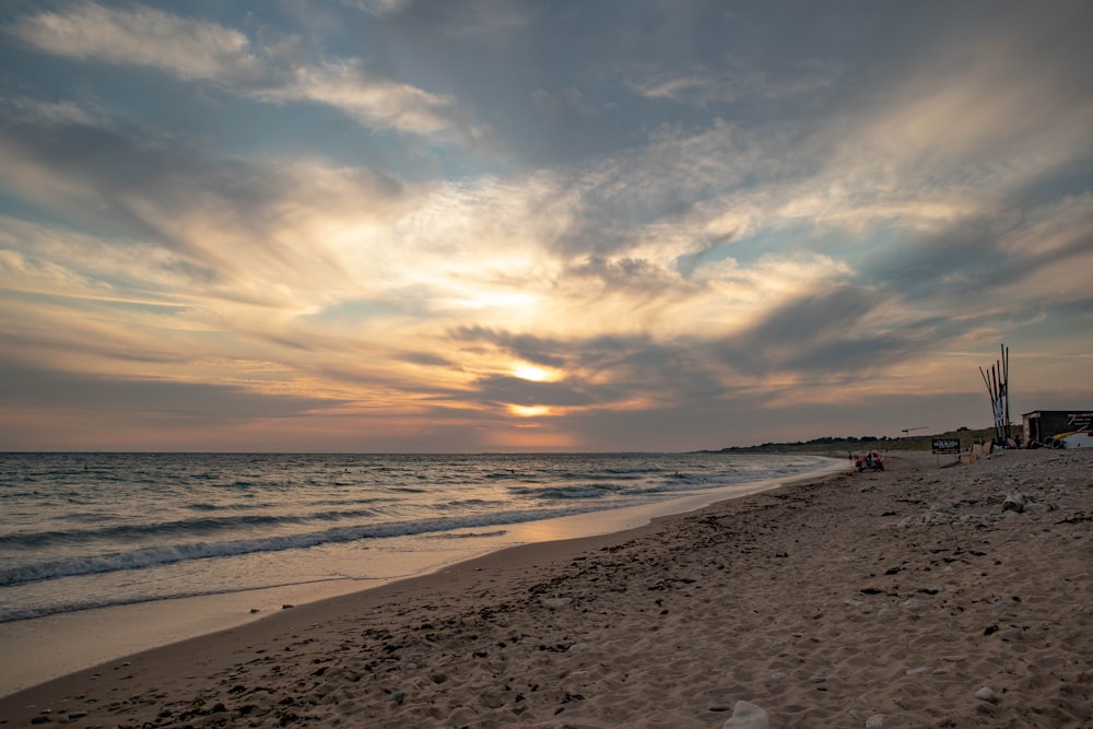 the sun is setting over the ocean on the beach