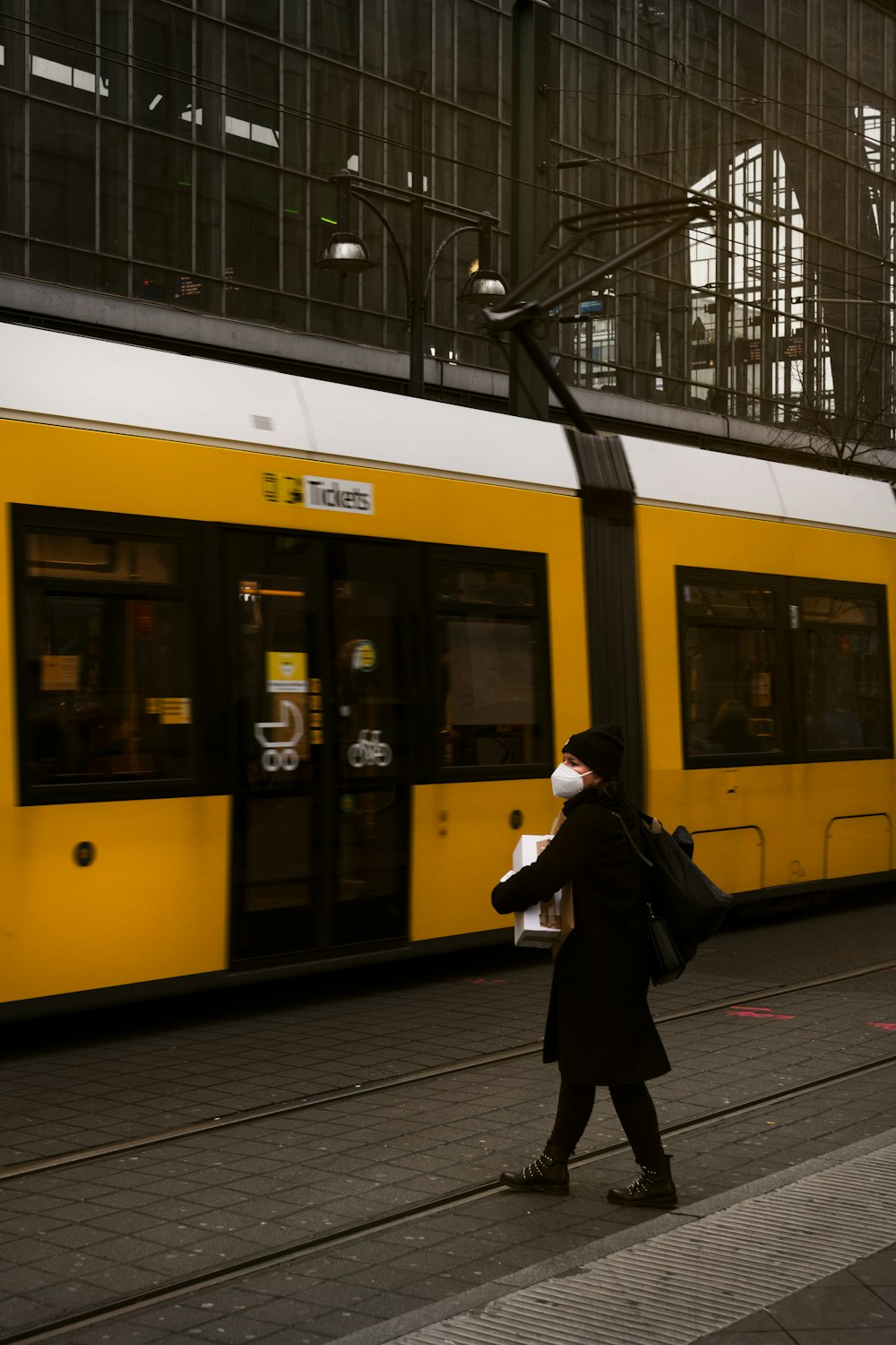 a woman walking down a sidewalk next to a yellow train