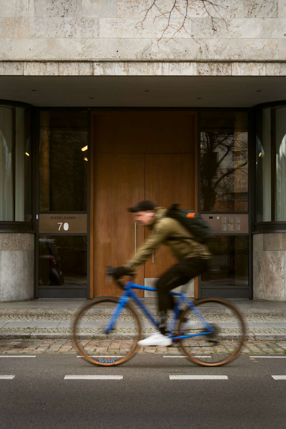 a man riding a bike down a street past a tall building