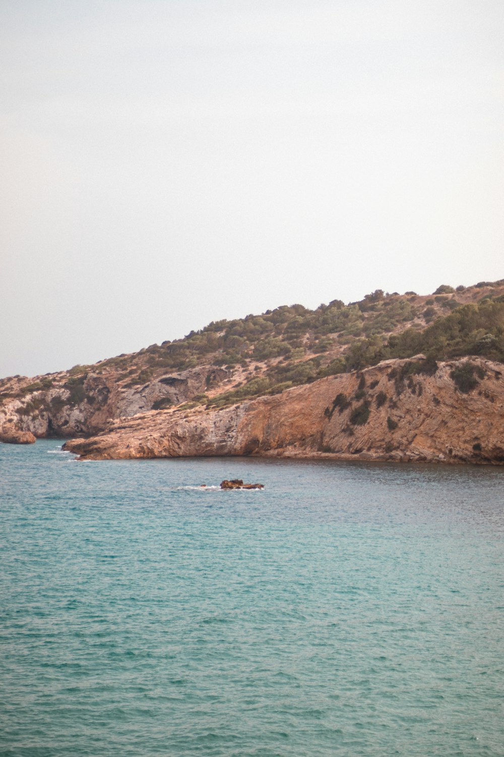 a body of water with a hill in the background