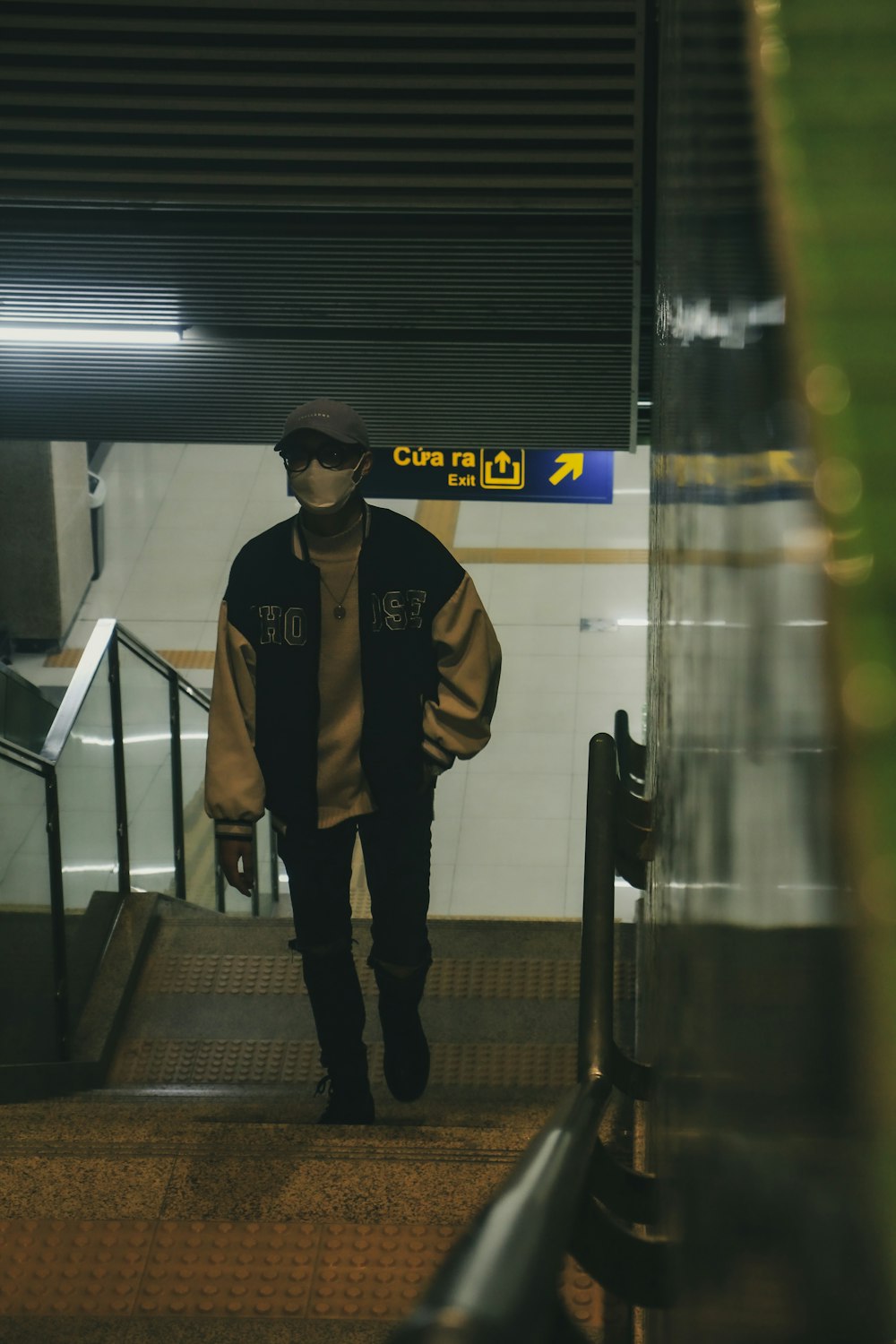 a man walking down an escalator with a hat on