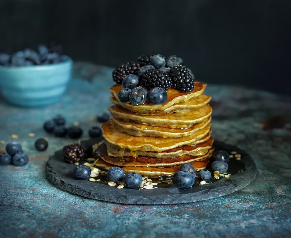 a stack of pancakes topped with berries and blueberries