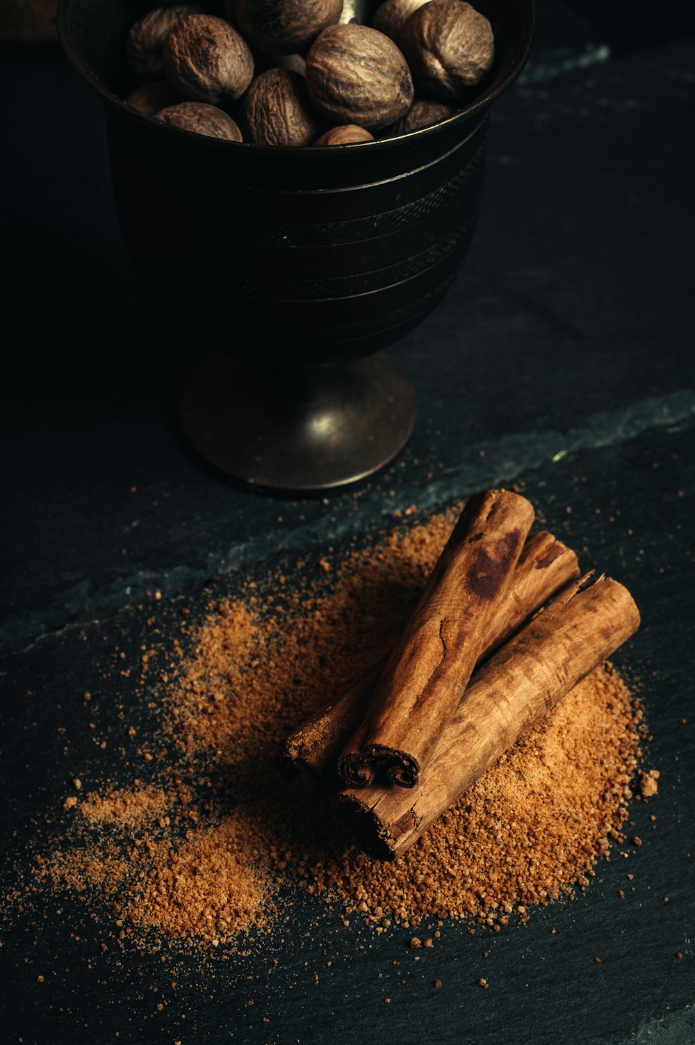 uma tigela de nozes e paus de canela em uma mesa