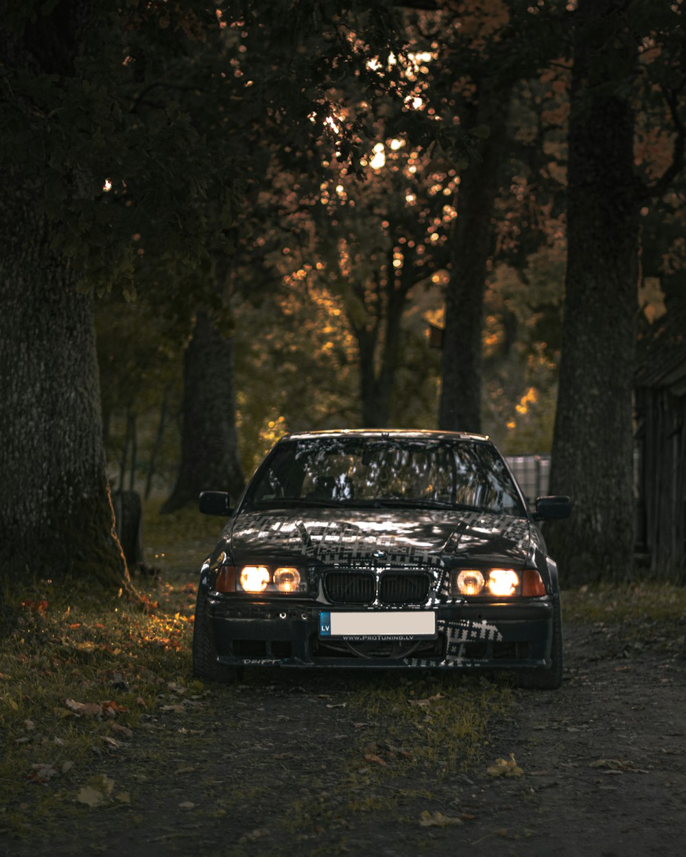 a black car parked in the middle of a forest