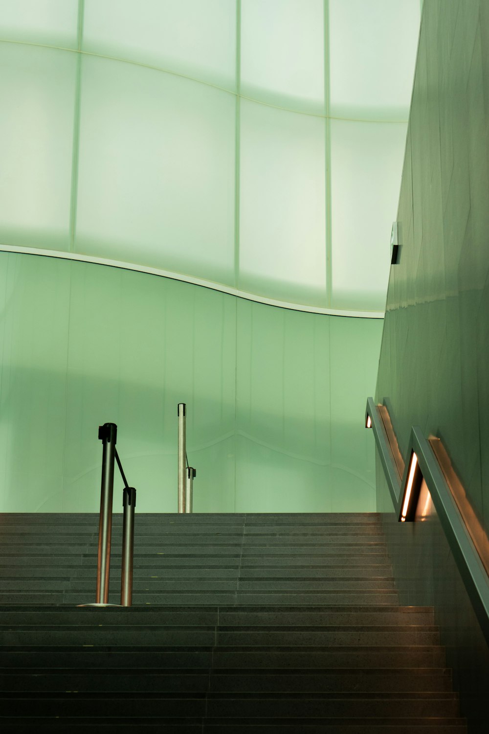 an escalator in a building with a green wall