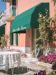a table and chairs outside of a pink building
