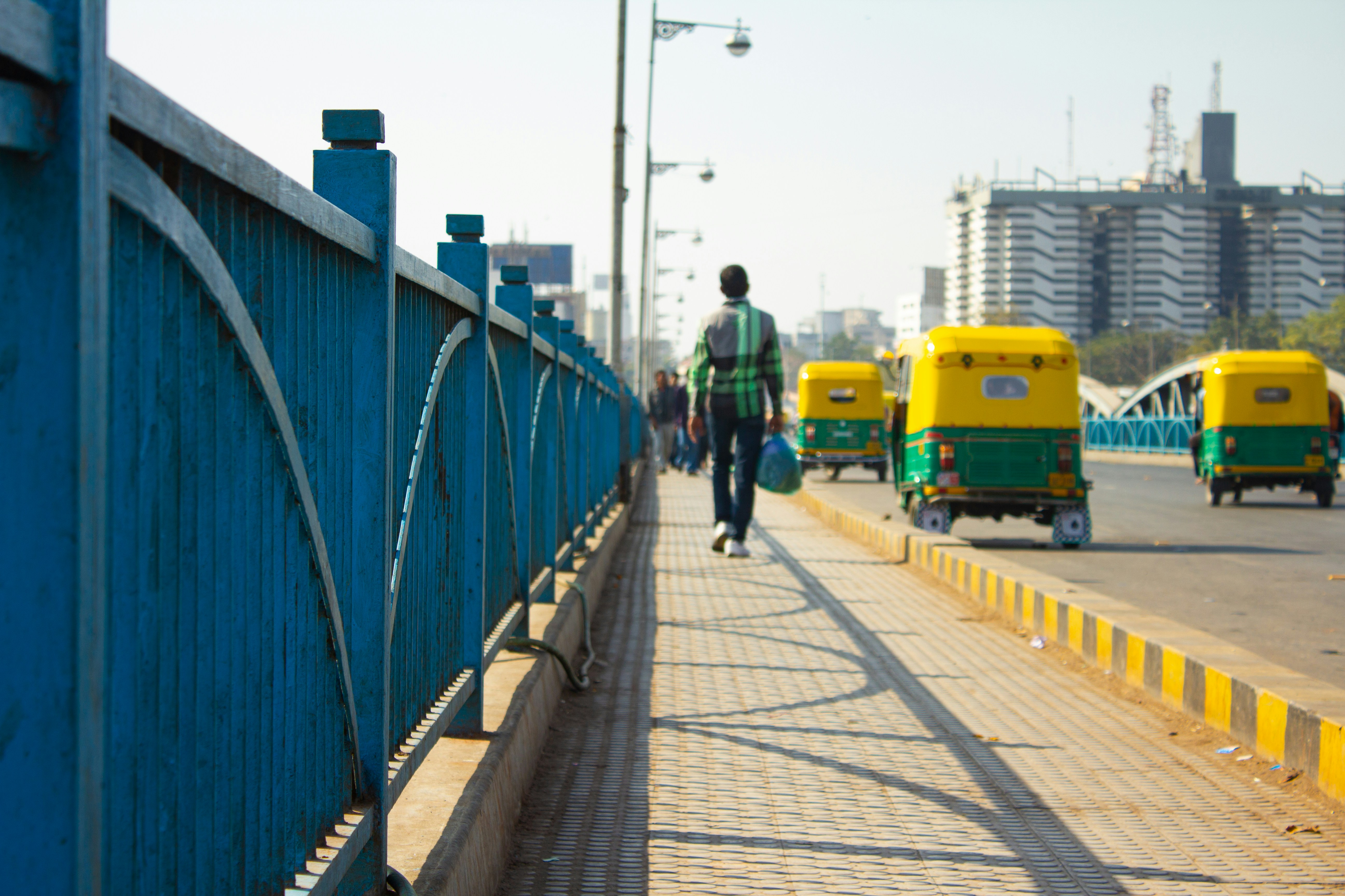 a man walking across a bridge over a street