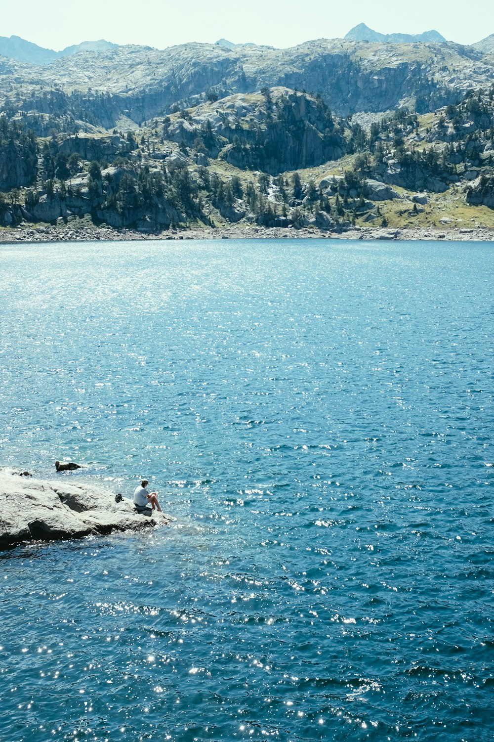 a person standing on a rock in the middle of a lake