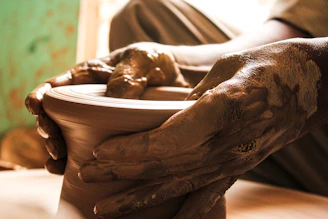 a person holding a clay bowl with their hands