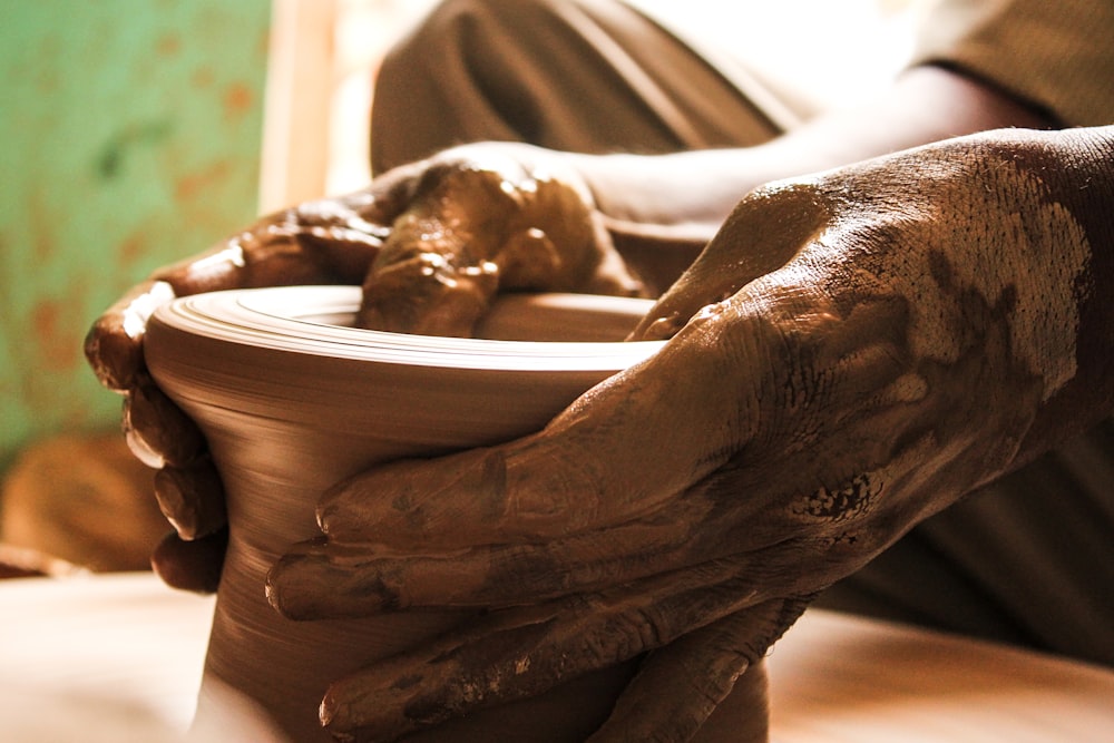 a person holding a clay bowl with their hands