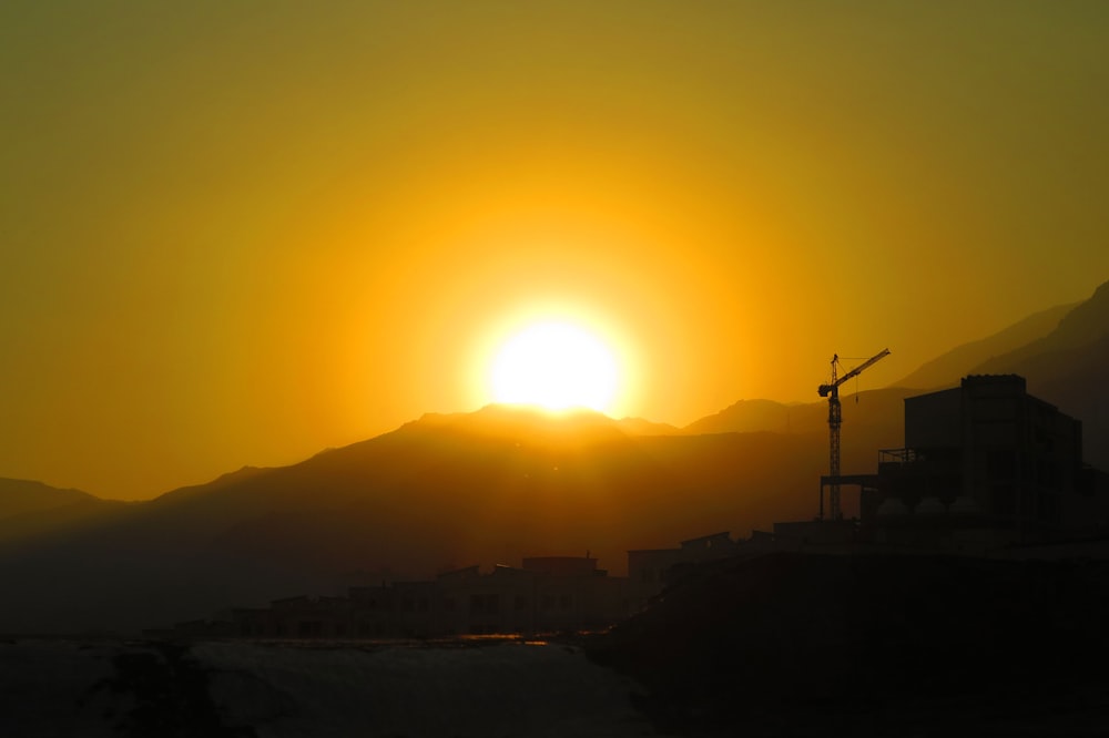 the sun is setting over a city with mountains in the background