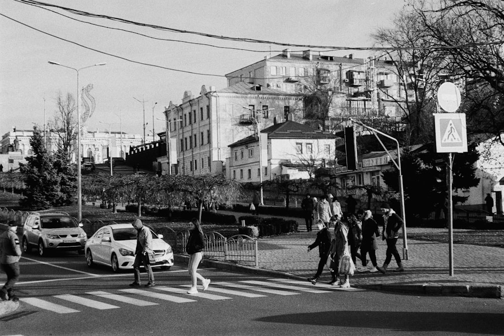 a black and white photo of people crossing the street