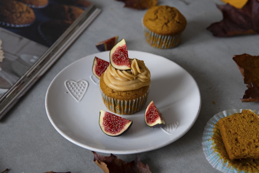 a white plate topped with a cupcake covered in frosting